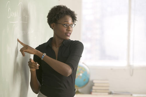 Image of teacher pointing to problems on a chalkboard.