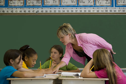 Image of a teacher helping a small group of students.